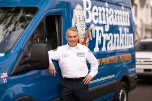 Benjamin Franklin Plumbing Tech, Joe, In front of his blue service van at a home in Niceville FL