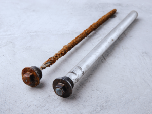 Old rusted anode rod next to an anode rod that hasn't been used