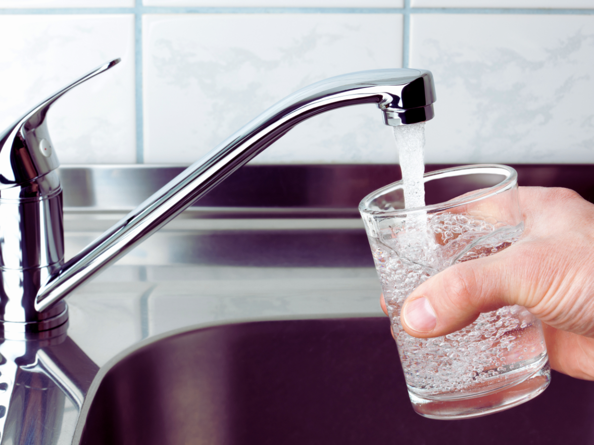 homeowner filling up glass cup with tap water from kitchen sink